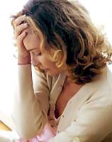 Mujer de mediana edad con cabeza inclinada y su mano derecha en su frente en actitud depresiva o preocupada